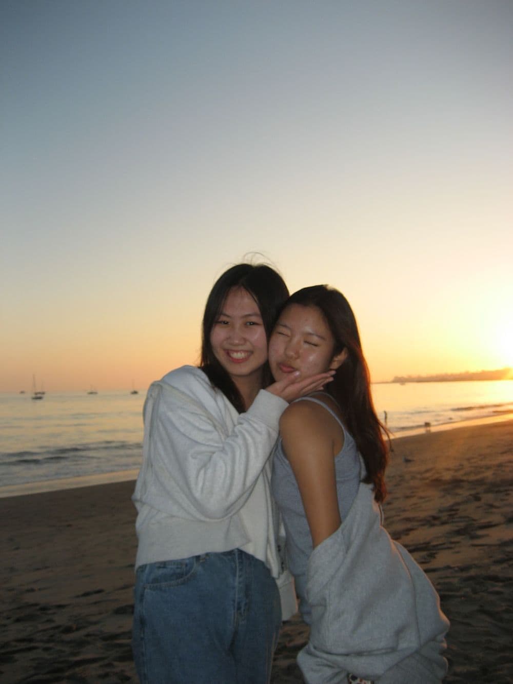 Two organizers hugging on the beach at sunset